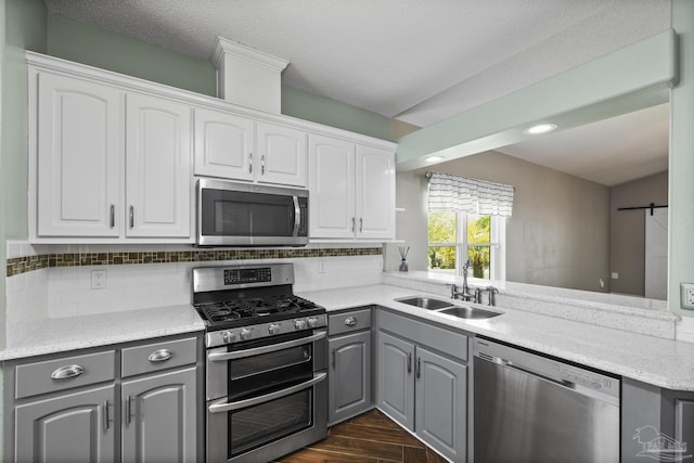 kitchen featuring dark wood-style floors, a sink, stainless steel appliances, gray cabinets, and white cabinets