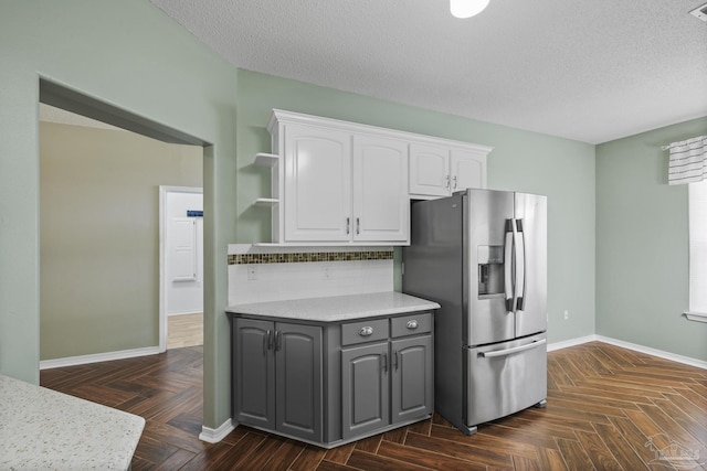 kitchen featuring baseboards, open shelves, stainless steel fridge with ice dispenser, white cabinets, and gray cabinetry