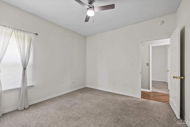 carpeted empty room with a ceiling fan, a textured ceiling, and baseboards
