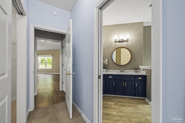 corridor with baseboards and a sink