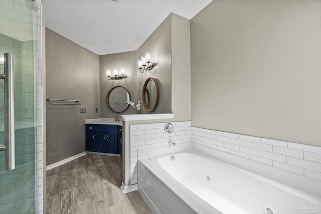 bathroom with a jetted tub, wood finished floors, vanity, and baseboards