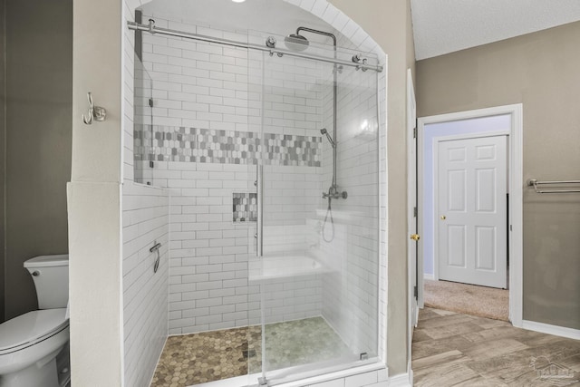 full bath with toilet, a stall shower, wood finished floors, and baseboards