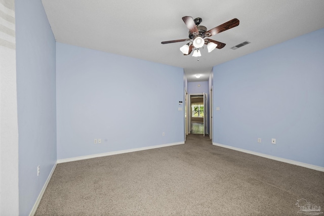 carpeted empty room featuring baseboards, visible vents, and ceiling fan