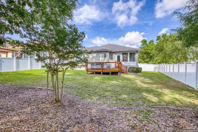 back of house featuring a deck, a yard, a sunroom, and a fenced backyard