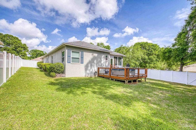 back of house featuring a lawn, brick siding, a wooden deck, and a fenced backyard