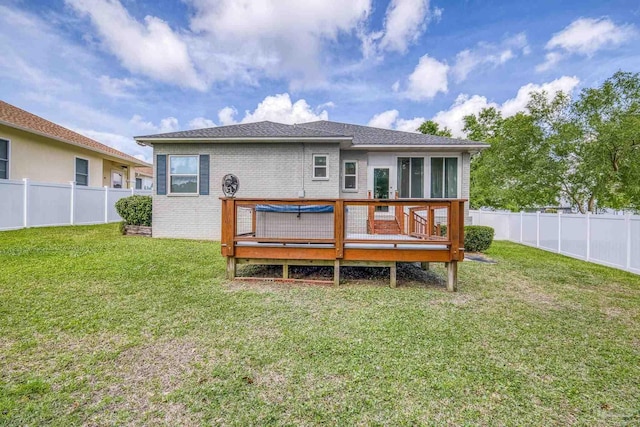 back of house with a deck, brick siding, a fenced backyard, and a yard