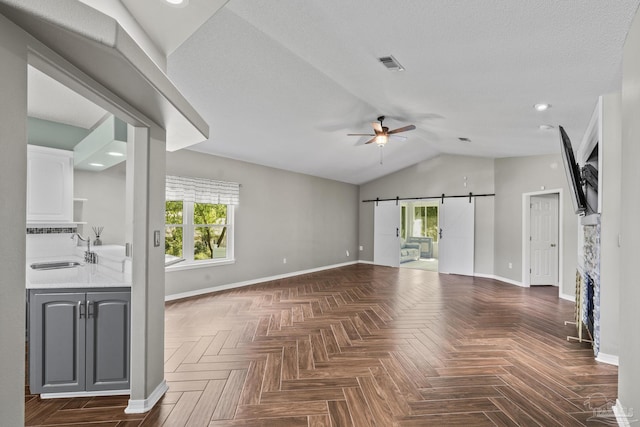 unfurnished living room featuring a wealth of natural light, ceiling fan, baseboards, and a sink