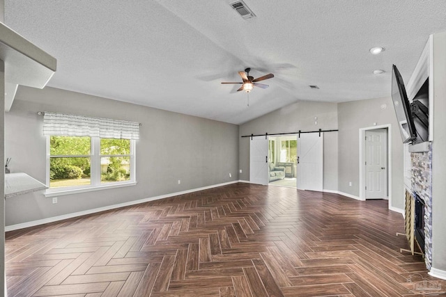 unfurnished living room featuring visible vents, ceiling fan, a barn door, and baseboards