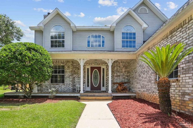 2724 Ashbury Ln, Cantonment, FL 32504 - view of front facade with a porch, brick siding, a chimney, and a front lawn