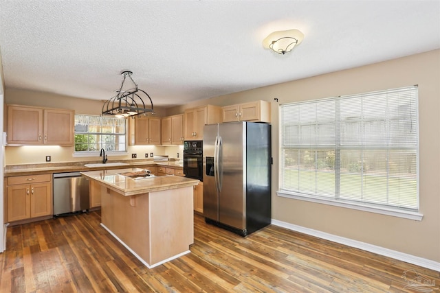 2724 Ashbury Ln, Cantonment, FL 32504 - kitchen featuring stainless steel appliances, light countertops, light brown cabinets, dark wood finished floors, and a kitchen island