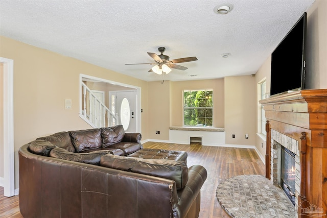 2724 Ashbury Ln, Cantonment, FL 32504 - living room with a glass covered fireplace, wood finished floors, a ceiling fan, stairs, and a textured ceiling