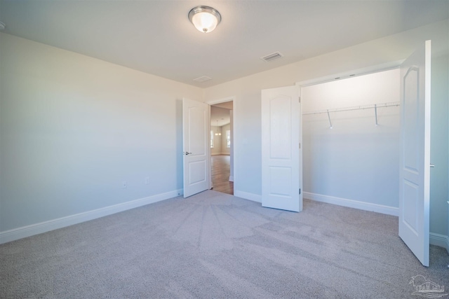 unfurnished bedroom featuring a closet and light colored carpet