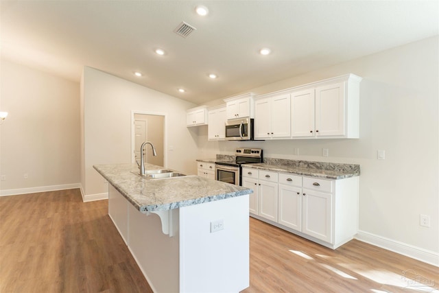 kitchen featuring stainless steel appliances, sink, an island with sink, and white cabinets