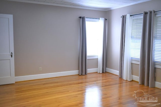 unfurnished room with light hardwood / wood-style floors, a wealth of natural light, and crown molding