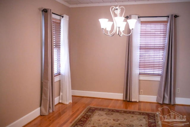 unfurnished room featuring hardwood / wood-style flooring, ornamental molding, and a notable chandelier