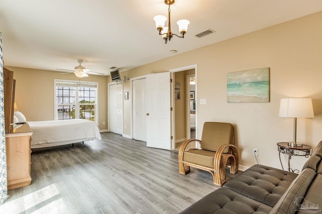 bedroom with a notable chandelier, multiple closets, and wood-type flooring