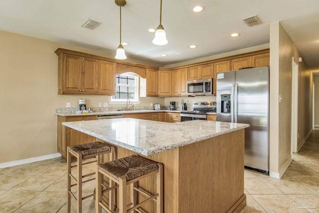 kitchen with light stone counters, appliances with stainless steel finishes, sink, pendant lighting, and a center island