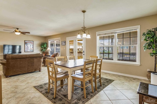 dining room with ceiling fan with notable chandelier, plenty of natural light, and light tile patterned floors