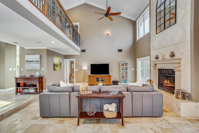 living room with ceiling fan, a fireplace, and a high ceiling