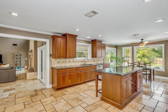 kitchen featuring a breakfast bar, tasteful backsplash, sink, dark stone countertops, and a center island