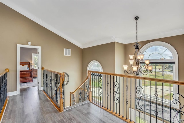 hall featuring lofted ceiling, hardwood / wood-style flooring, crown molding, and a chandelier