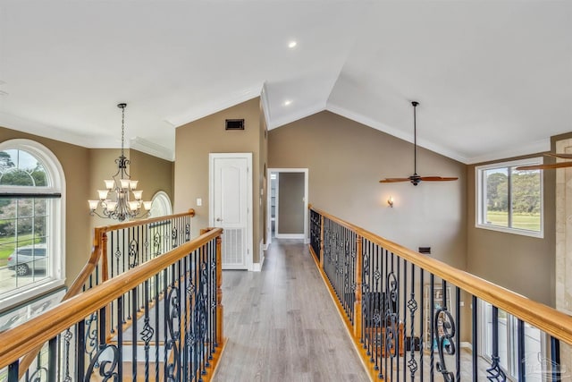 corridor with an inviting chandelier, ornamental molding, wood-type flooring, and lofted ceiling