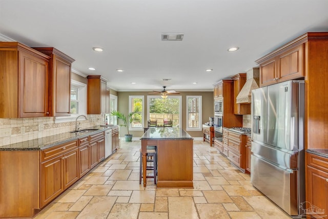 kitchen with sink, a breakfast bar, stainless steel appliances, a center island, and custom range hood