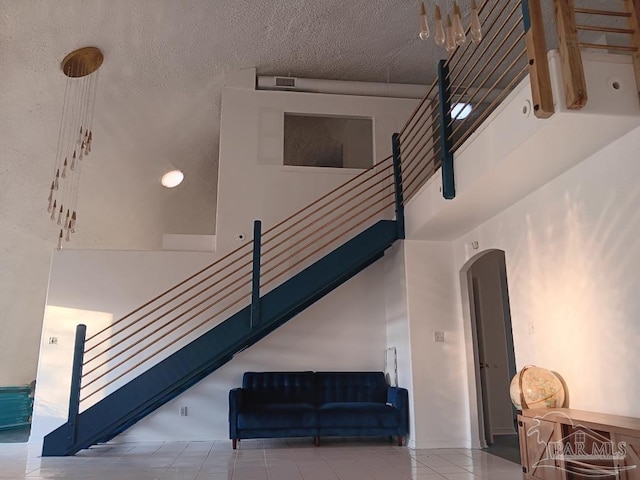 staircase with tile patterned flooring and a towering ceiling