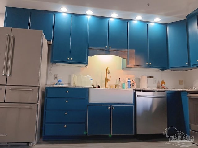 kitchen featuring blue cabinetry, light stone countertops, sink, and appliances with stainless steel finishes