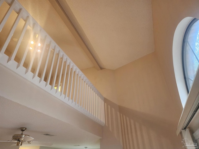 staircase featuring a high ceiling, beamed ceiling, and ceiling fan