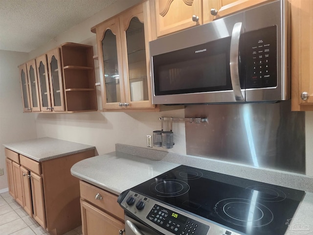 kitchen featuring a textured ceiling, appliances with stainless steel finishes, and light tile patterned flooring