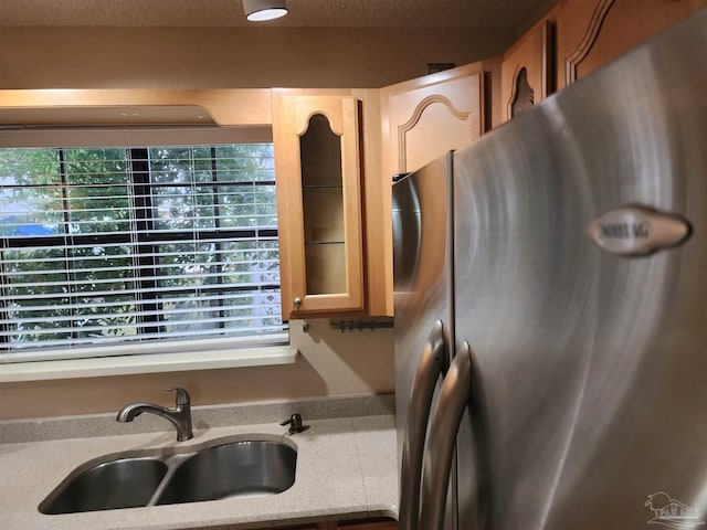 kitchen with a wealth of natural light, stainless steel refrigerator, and sink