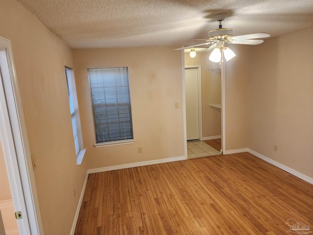 unfurnished room with light wood-type flooring, a textured ceiling, and ceiling fan