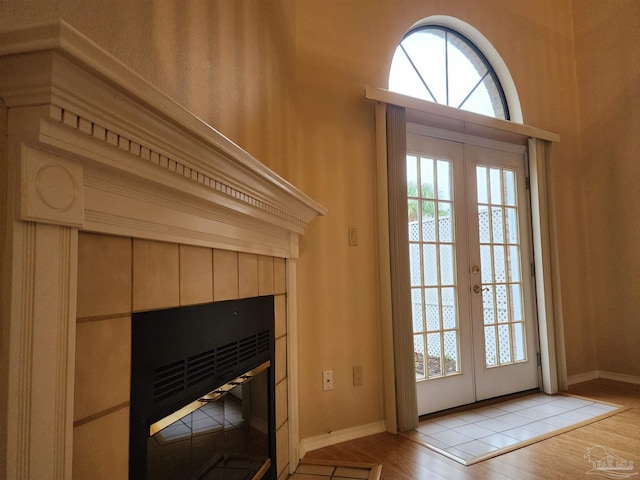 doorway to outside with light hardwood / wood-style floors, a tiled fireplace, and french doors