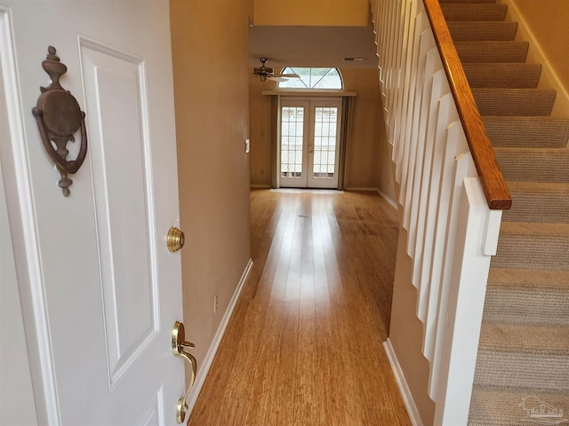 corridor with light hardwood / wood-style flooring and french doors