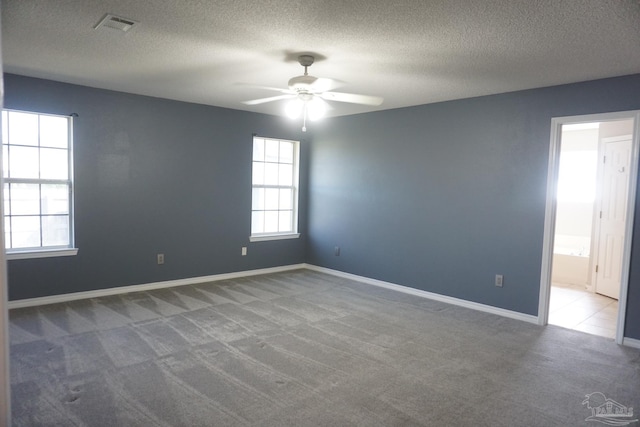 carpeted spare room with ceiling fan and a textured ceiling