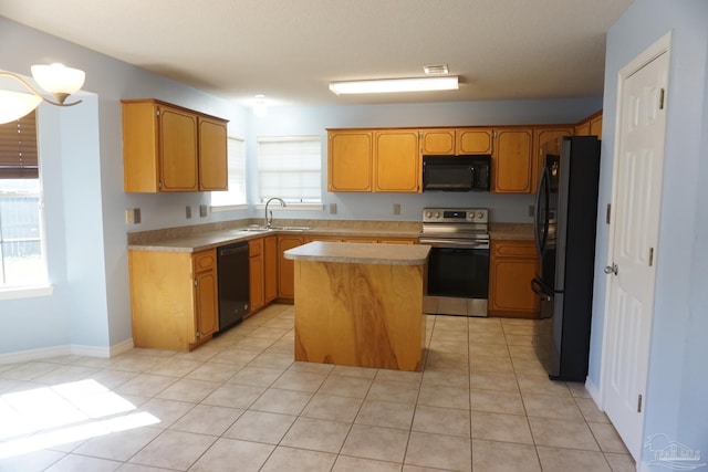 kitchen featuring black appliances, a center island, light tile patterned floors, and sink