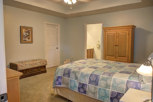 carpeted bedroom with ensuite bathroom and a tray ceiling