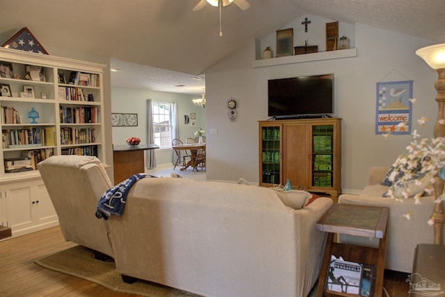 living room with wood-type flooring, ceiling fan with notable chandelier, and vaulted ceiling