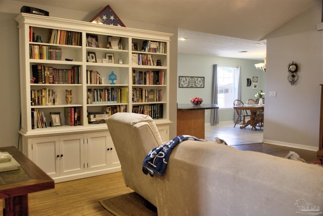 living area featuring a chandelier, light hardwood / wood-style flooring, and lofted ceiling