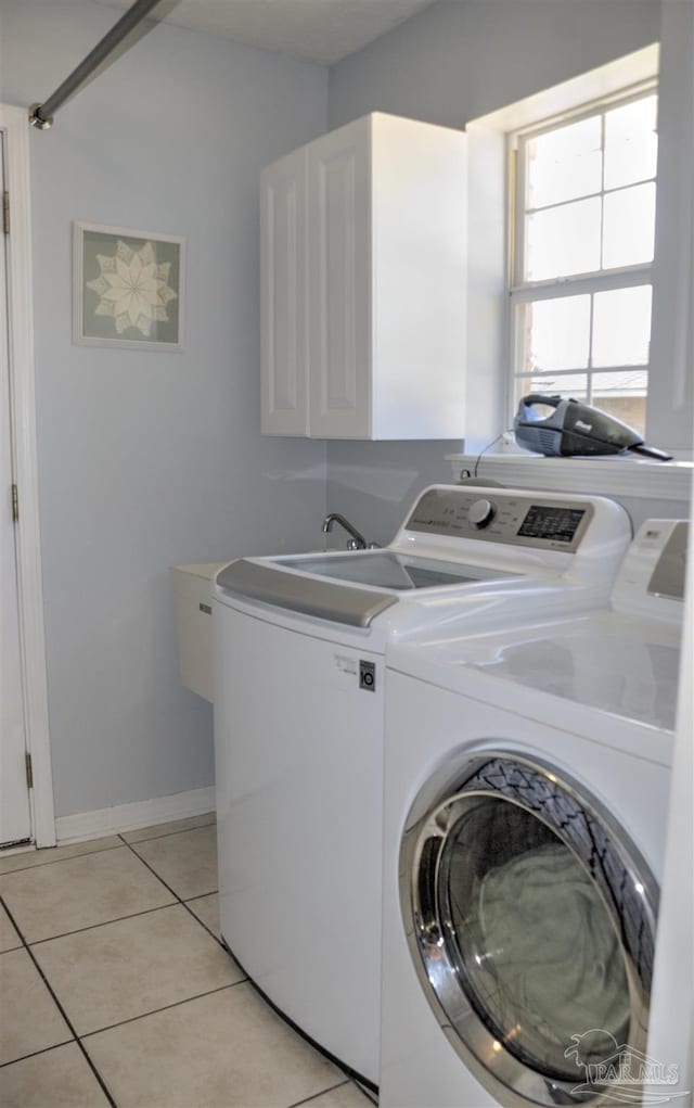 clothes washing area with cabinets, light tile patterned flooring, and washer and dryer