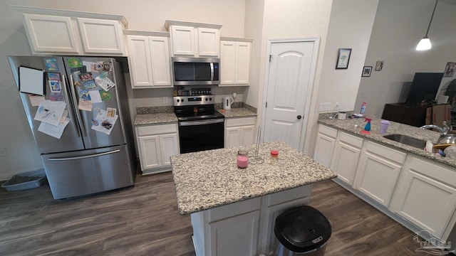 kitchen with light stone counters, dark wood-style floors, appliances with stainless steel finishes, white cabinetry, and a sink