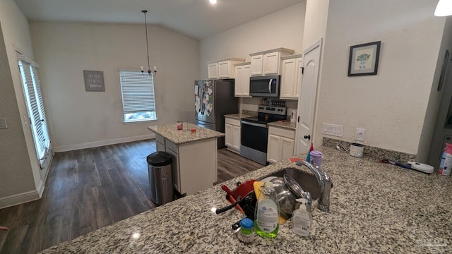 kitchen featuring lofted ceiling, light stone counters, stainless steel appliances, dark wood-type flooring, and a kitchen island