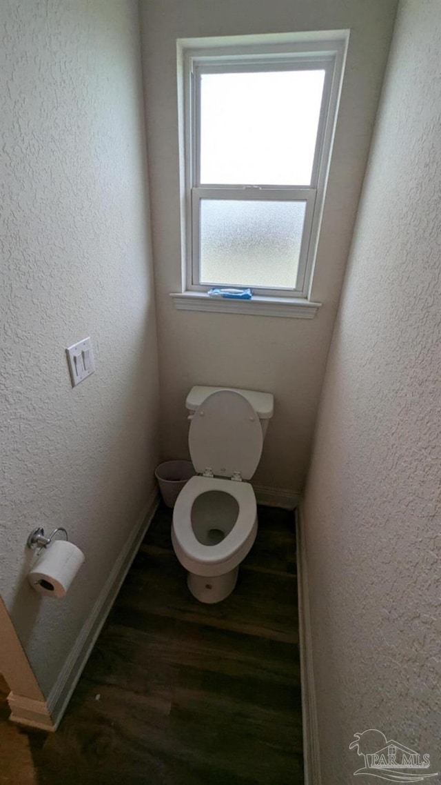 bathroom featuring toilet, baseboards, wood finished floors, and a textured wall