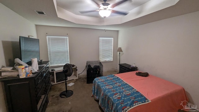 bedroom with visible vents, a tray ceiling, and ceiling fan