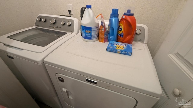 laundry room featuring a textured wall and washer and clothes dryer