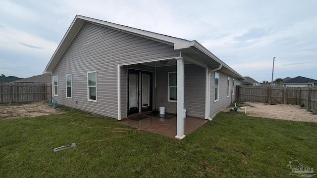 rear view of property with a fenced backyard, a lawn, and a patio