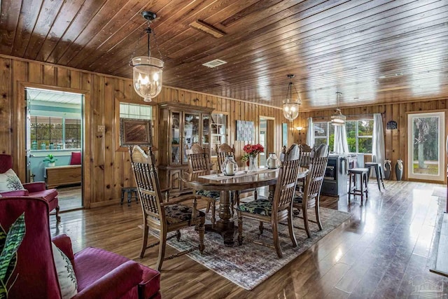 dining area featuring hardwood / wood-style flooring, a notable chandelier, and wood walls