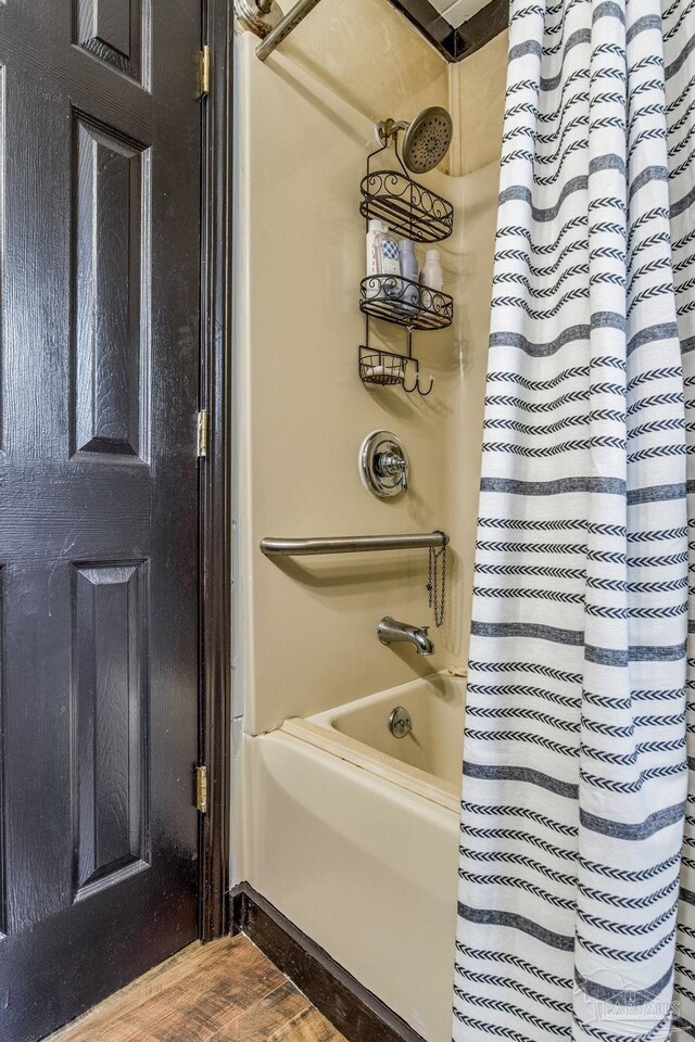 bathroom with hardwood / wood-style floors and shower / bathtub combination with curtain