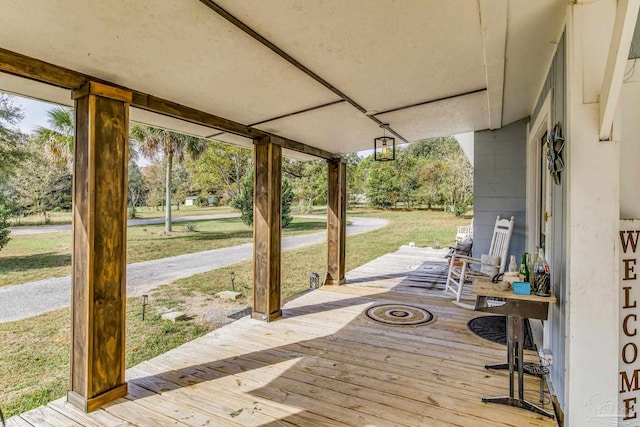 wooden terrace featuring a porch and a lawn